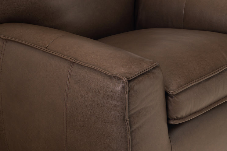 Brown leather sofa with a close-up view of the armrest and seat.